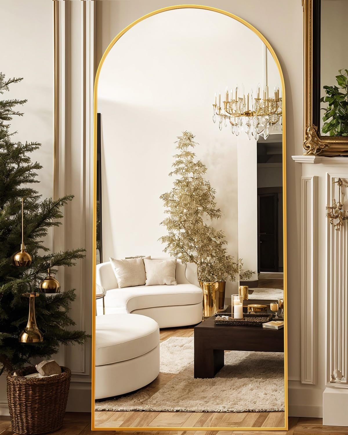 Tall arched full-length mirror with a thin gold frame reflecting a plush living room scene.