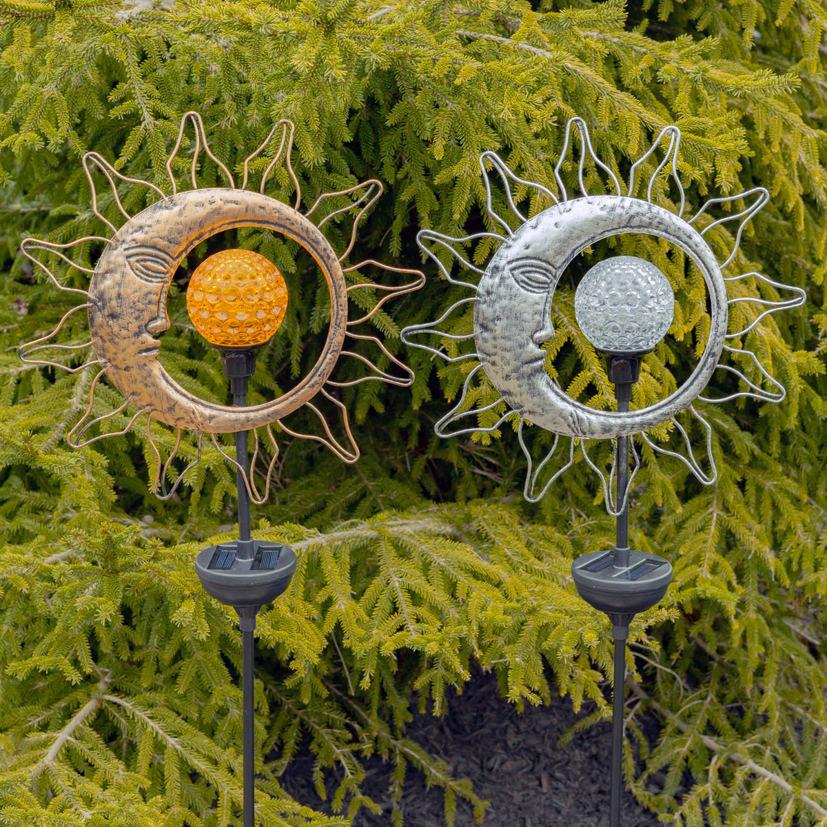 Gold and silver sun-and-moon ornaments with textured central globes and radiating wire rays, shown against greenery.