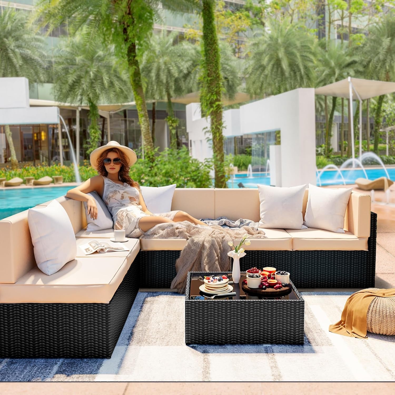 Poolside scene with dark rattan L-shaped sectional and beige cushions with a lounging figure on the sofa