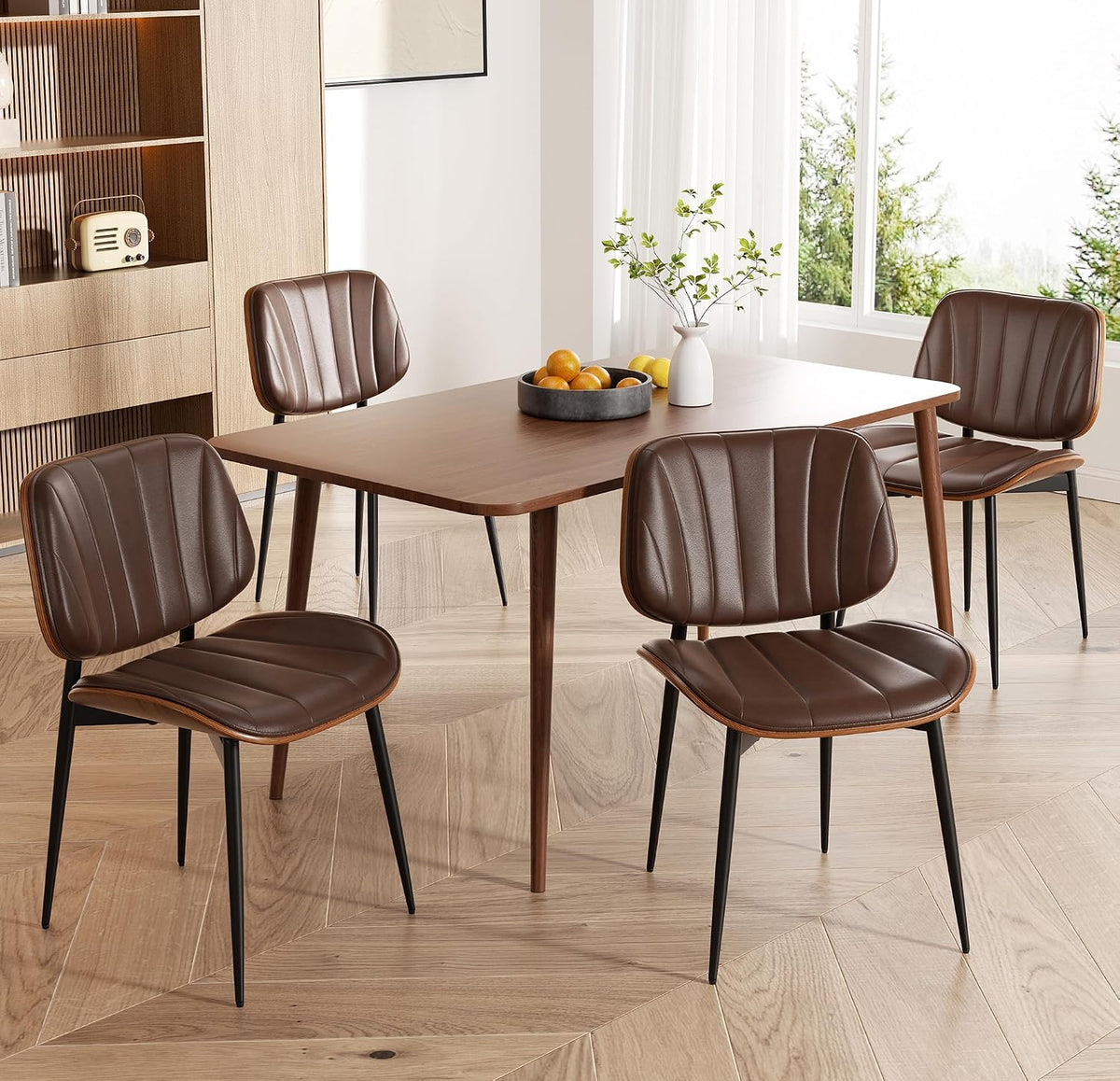 Close side view of two brown faux-leather chairs at a walnut dining table on herringbone wood floor.