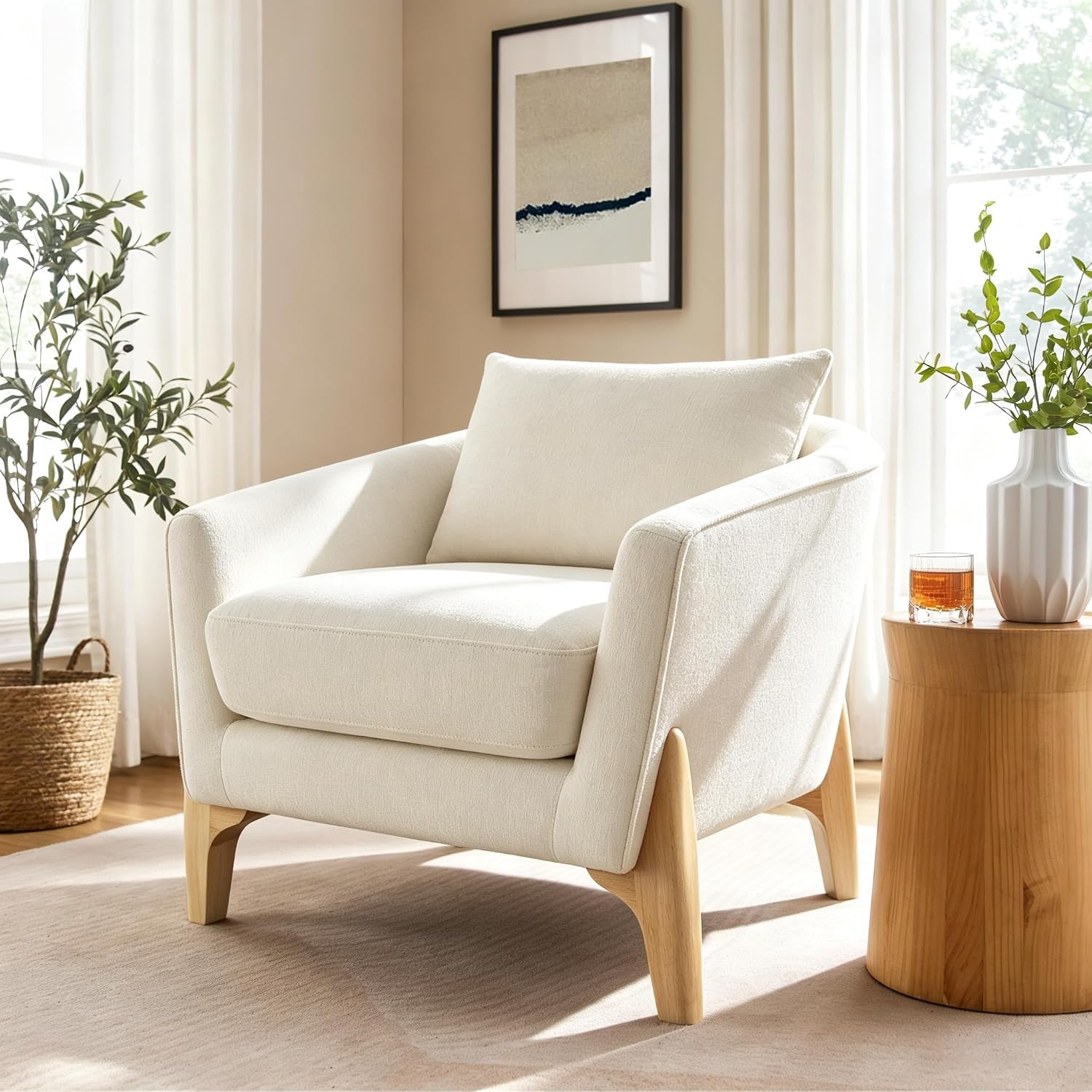 Single ivory oversized fleece accent chair with curved arms and light wood legs next to a small wood table and vase.