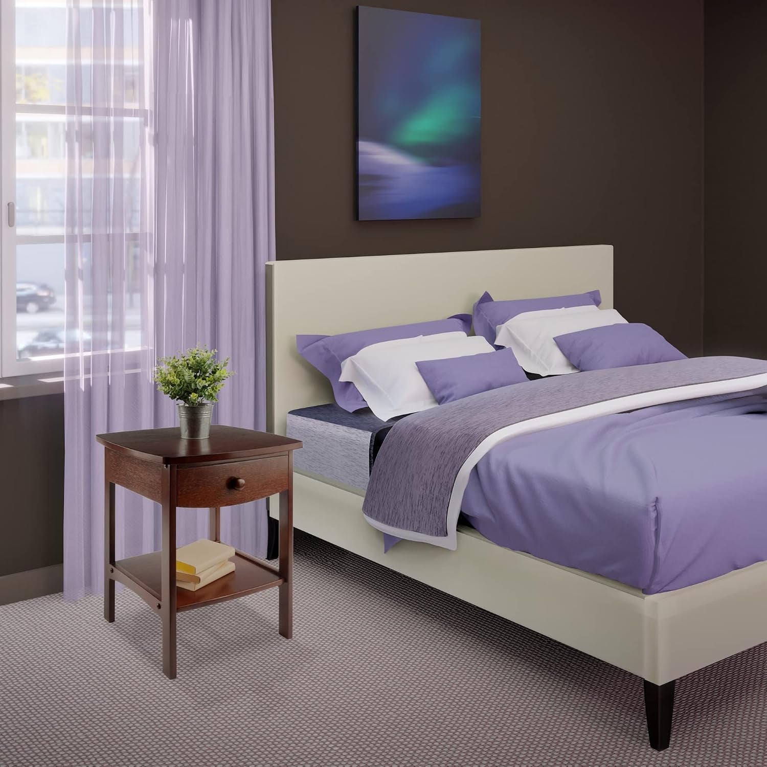 Walnut finish end table staged beside a bed in a bedroom setting with curtains and a plant