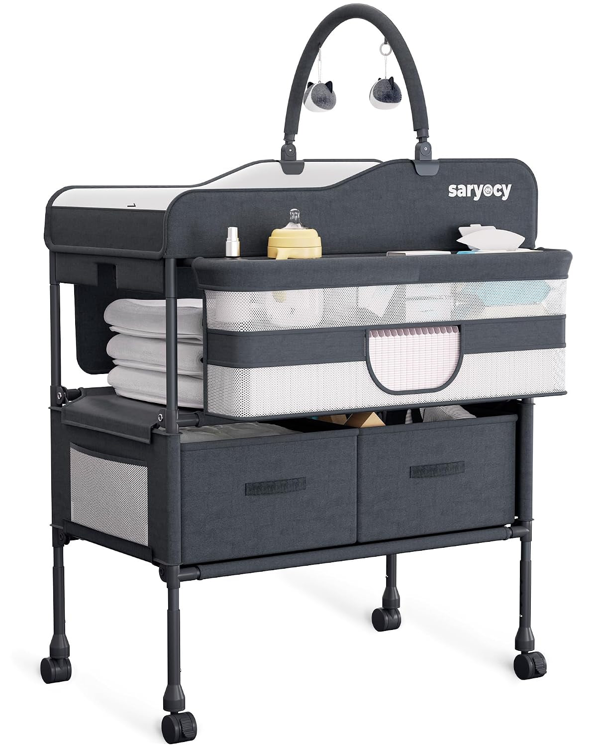Three-quarter studio view of a dark gray mobile changing table with toy arch, mesh-front storage and two fabric drawers