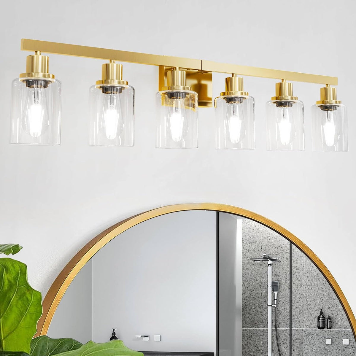 Five-light brass vanity fixture with clear cylindrical glass shades above a round mirror