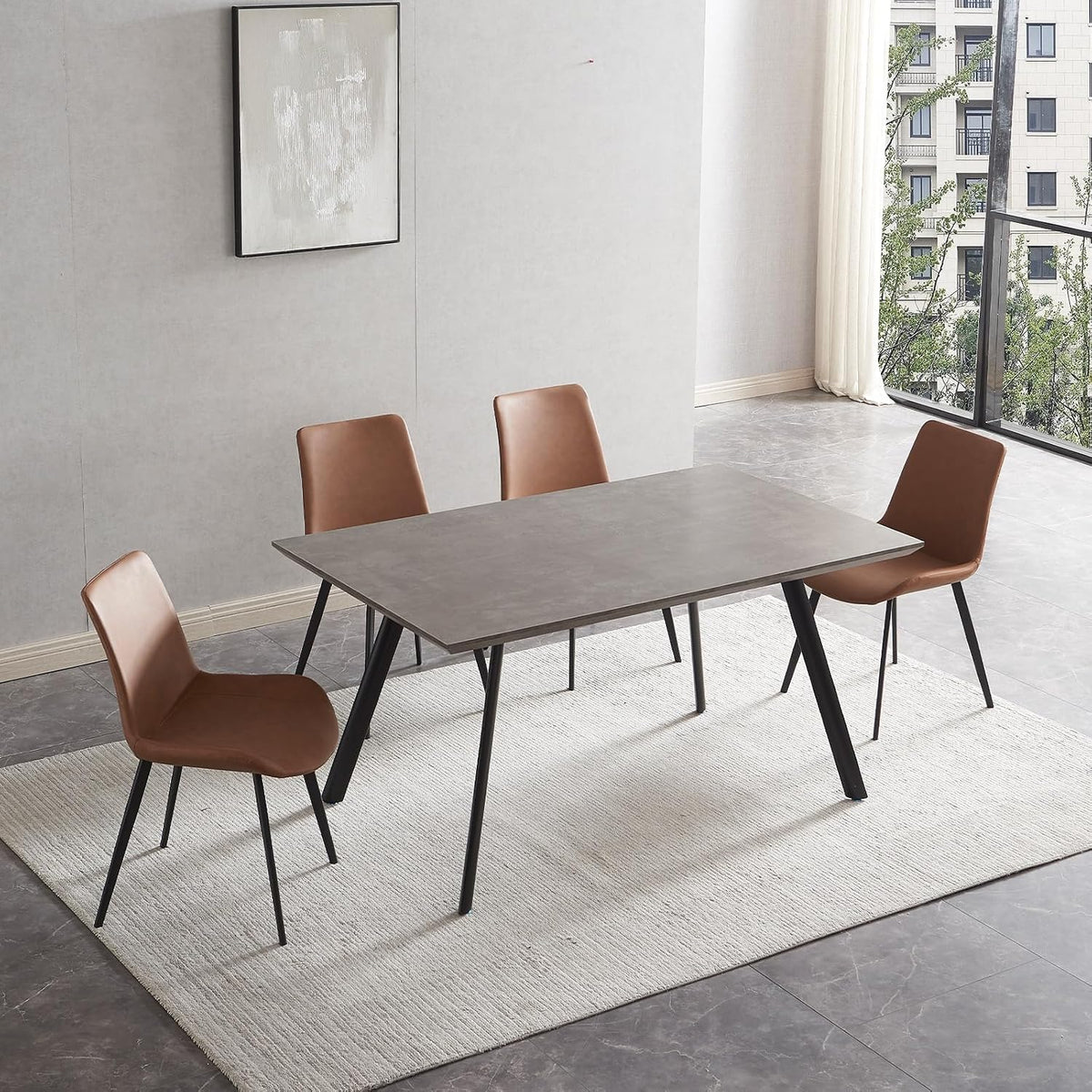 Side perspective of a gray table top paired with brown PU chairs next to a large window and light rug.