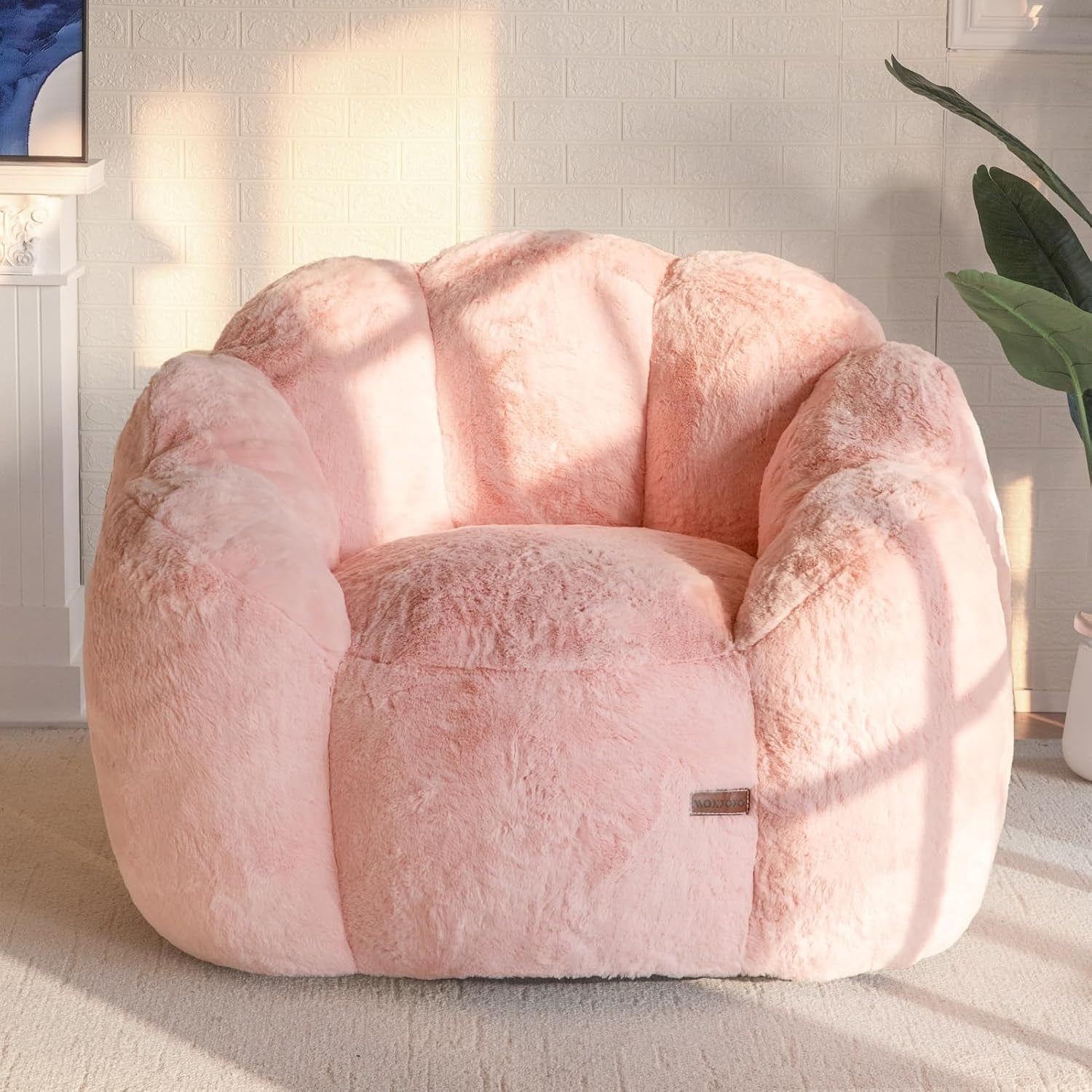 Front-facing close view of a single pink plush floral-shaped bean bag chair in a bright room.