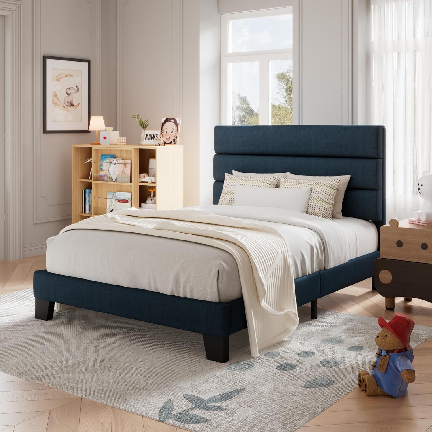 Three-quarter room view of a navy blue upholstered bed in a bright children's bedroom.