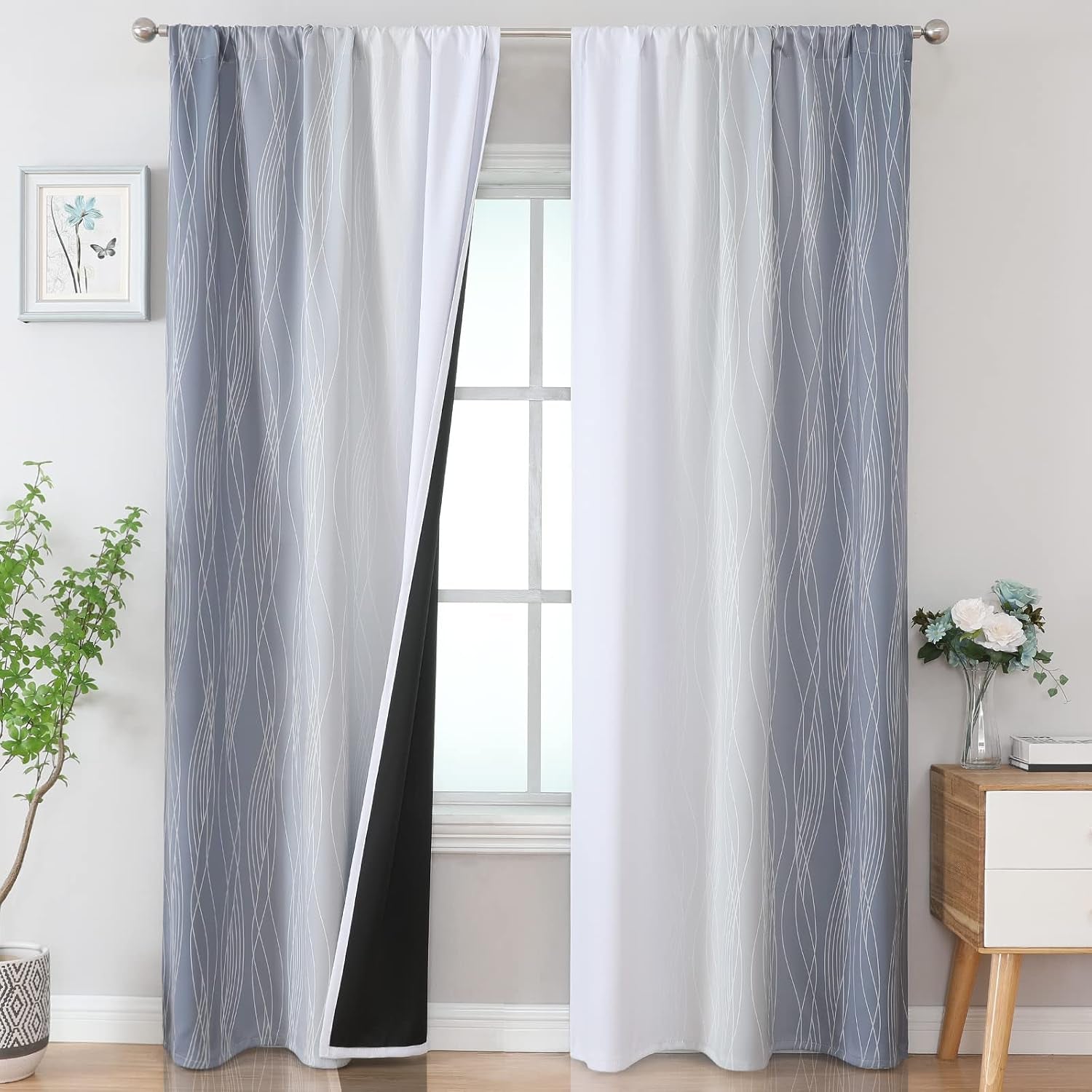 Window dressed with blue-gray ombre curtain panels with white wavy line pattern and black backing peeking out