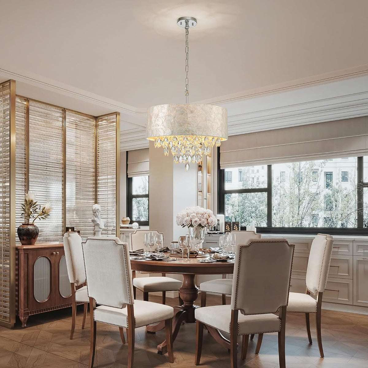 Dining room scene with the chandelier hanging above a round table set for dinner in a neutral interior.