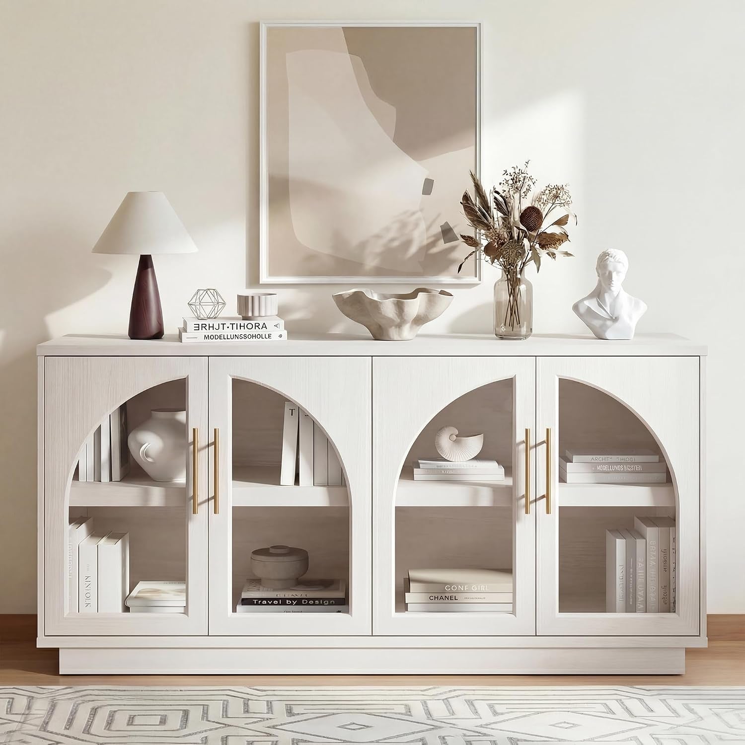 Front-facing white buffet sideboard with arched glass doors styled with books and decorative objects