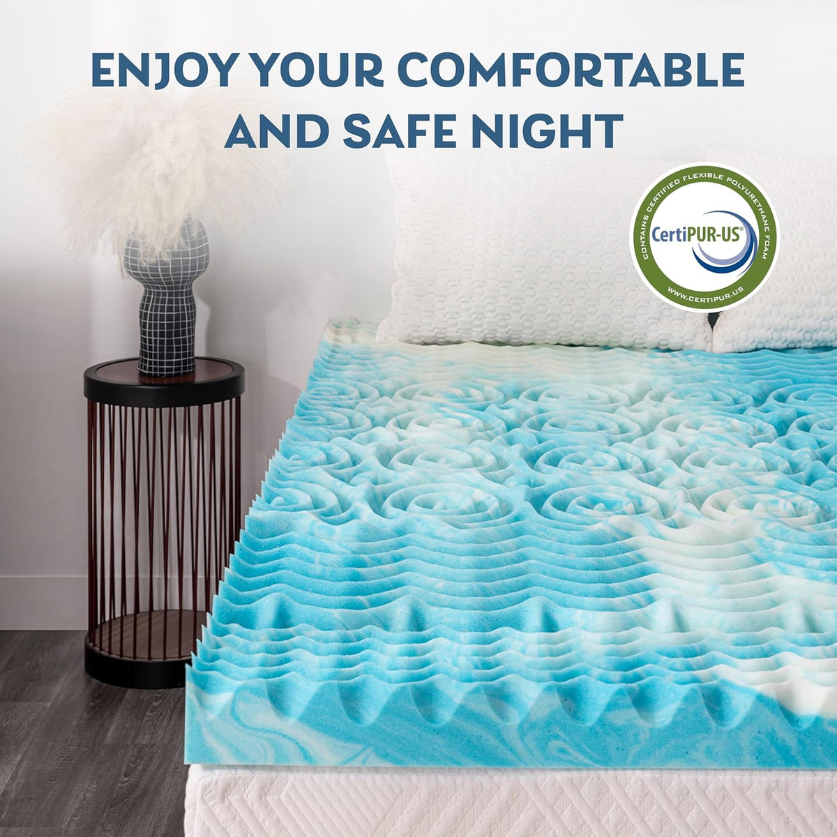 Angled view of the blue-and-white egg-crate topper covering a mattress with two textured white pillows and a bedside table