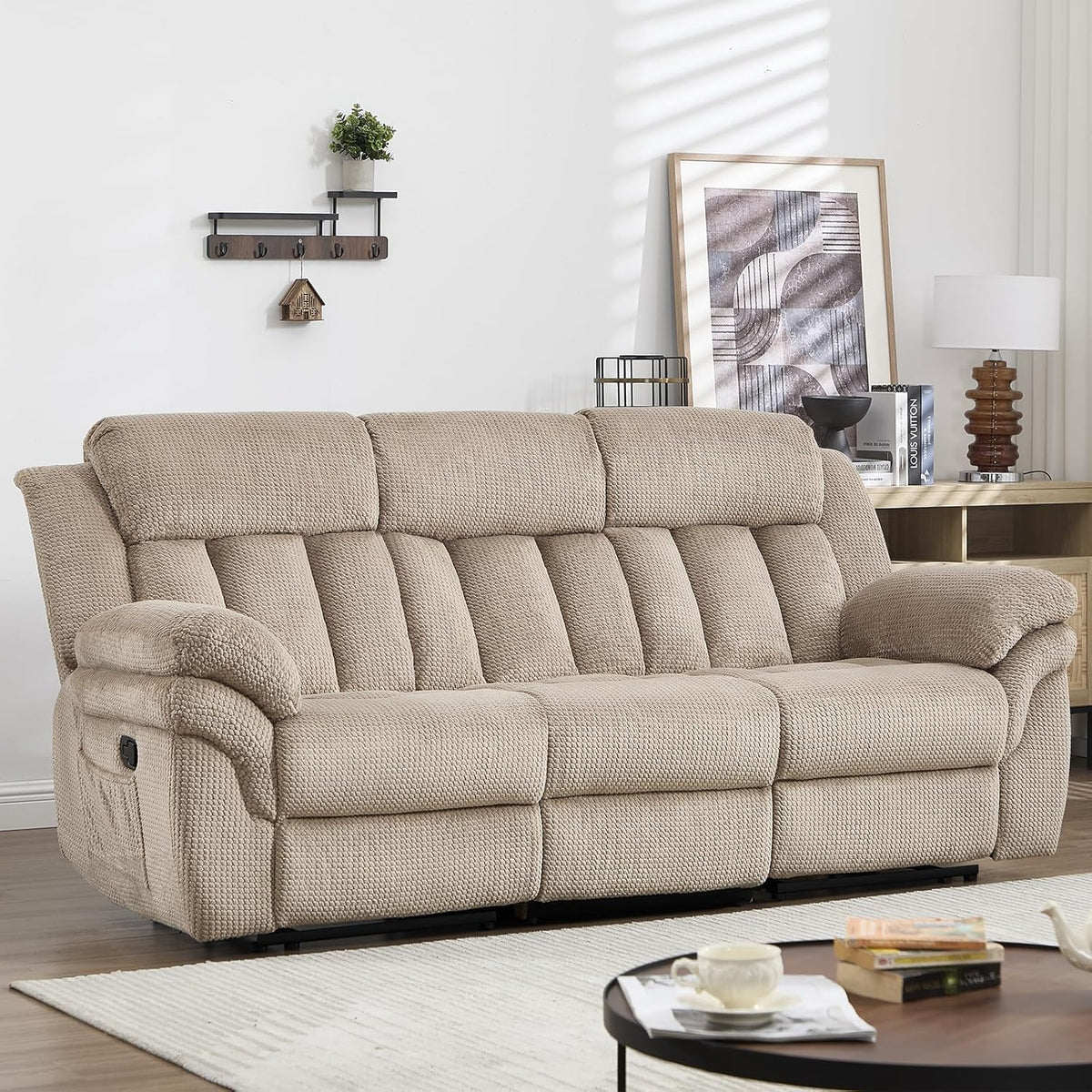 Angled view of a light brown three-seat recliner sofa in a staged living room