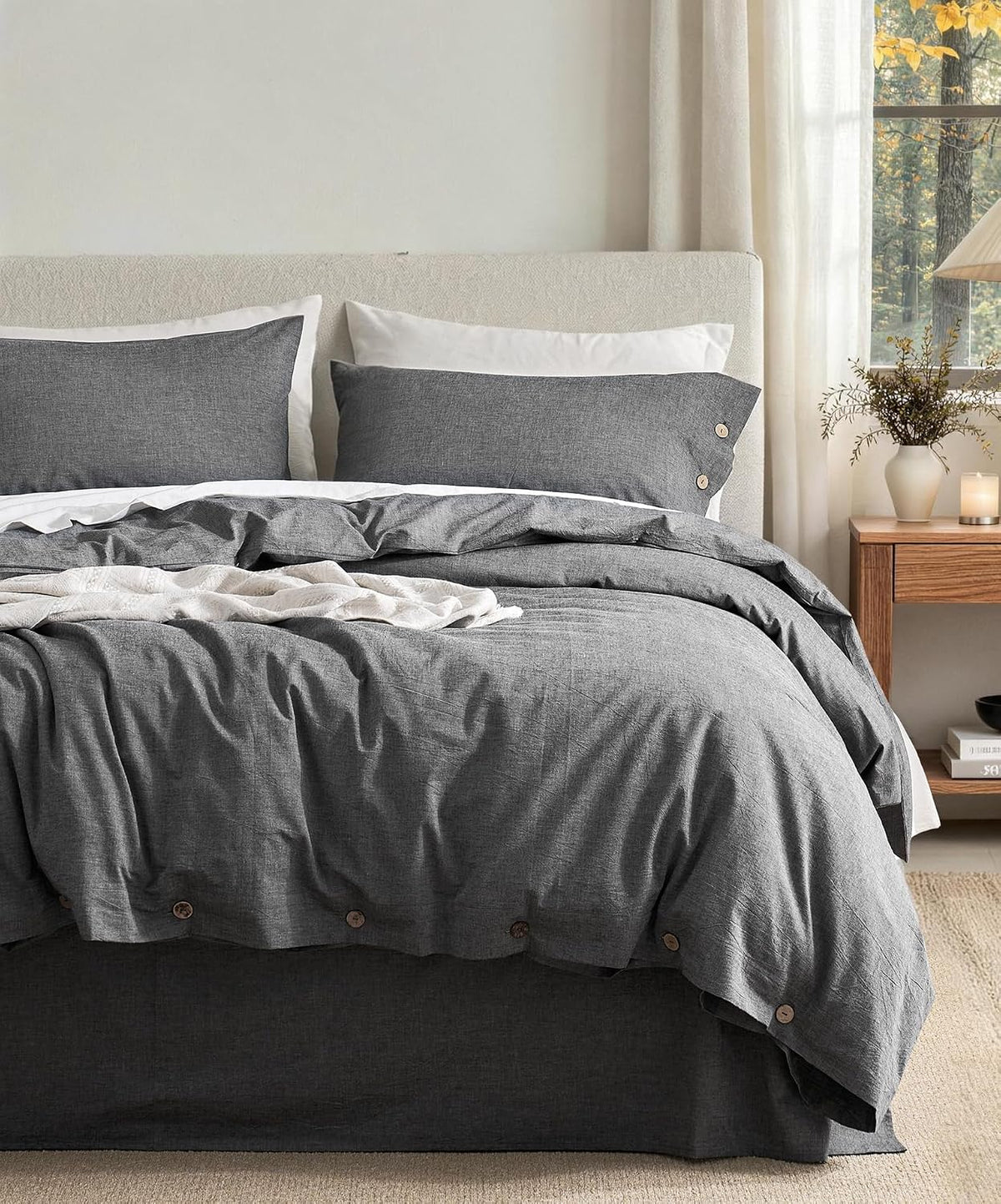 Bed made with dark charcoal washed-cotton duvet and matching pillow shams, wooden nightstand at right