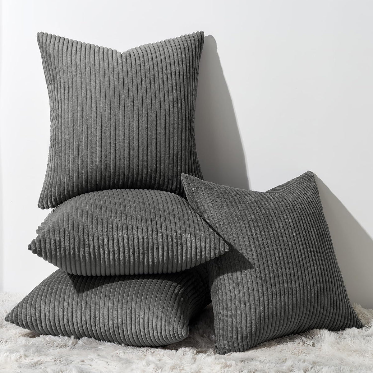 Five ribbed corduroy pillows in fall colors—green, orange, yellow, tan—grouped on a sofa.