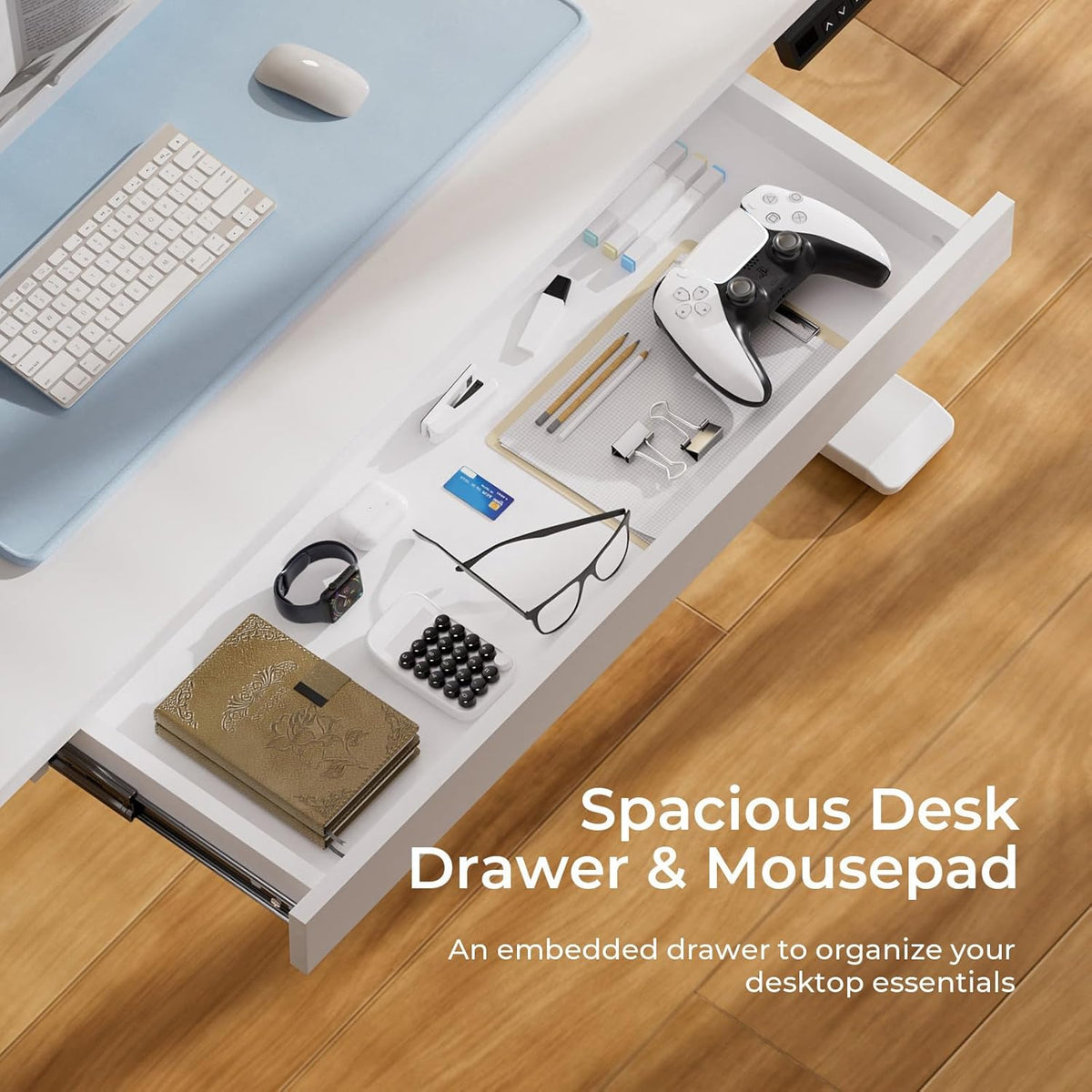 Overhead close-up of the desk’s open shallow drawer holding glasses, controller and notebooks