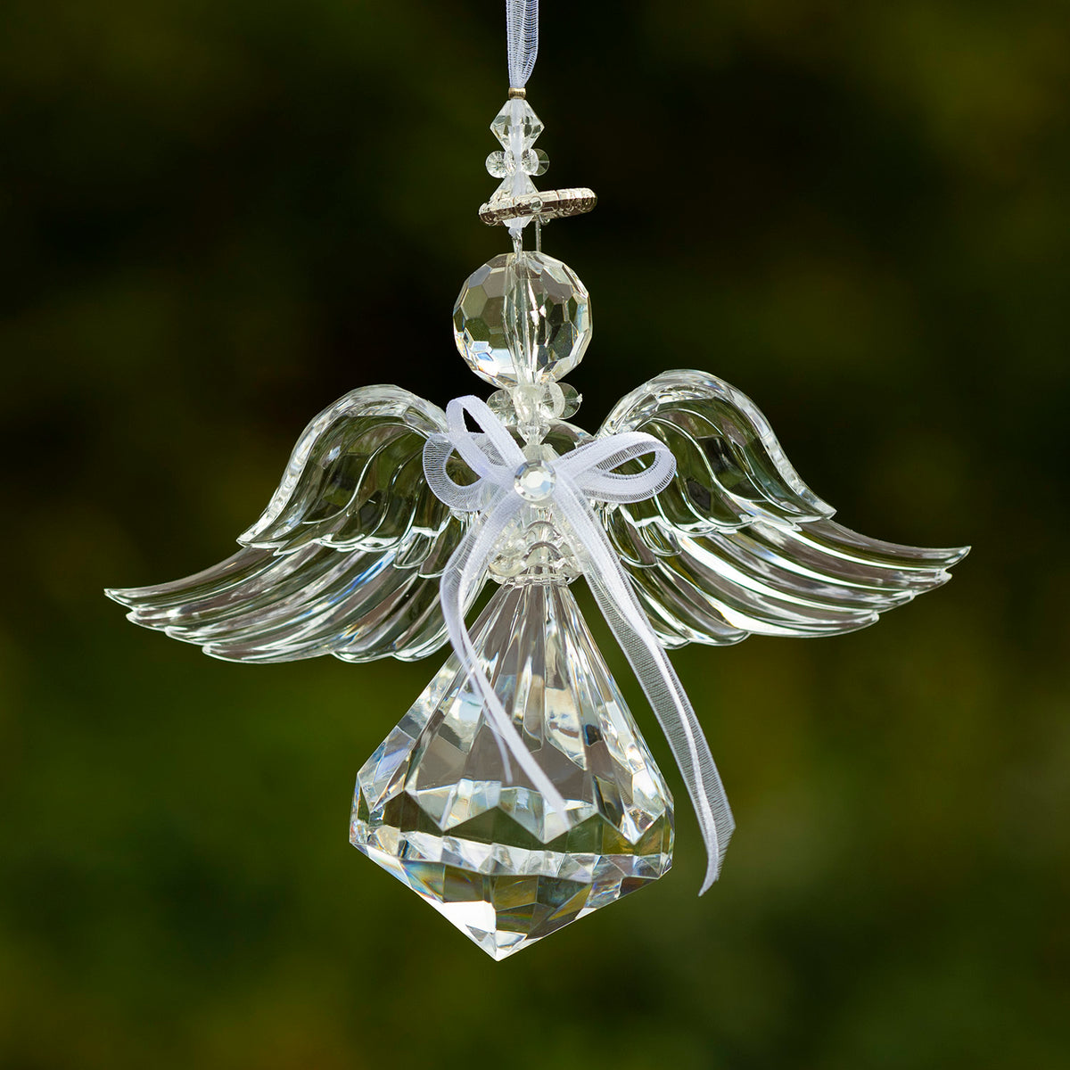 Clear angel ornament viewed with wings spread wide and a large faceted skirt below its white bow.