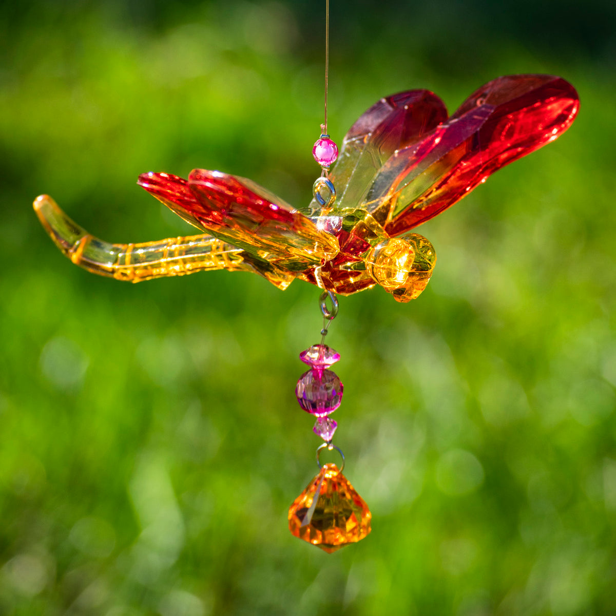 Close-up of an orange and red dragonfly ornament with pink and amber beads.