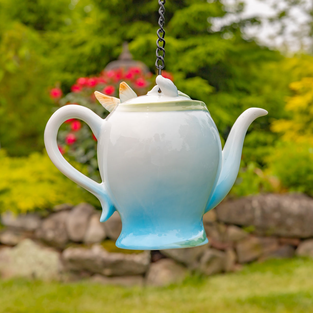 Plain pale blue-and-white back of the hanging teapot, with its handle and curved spout visible.