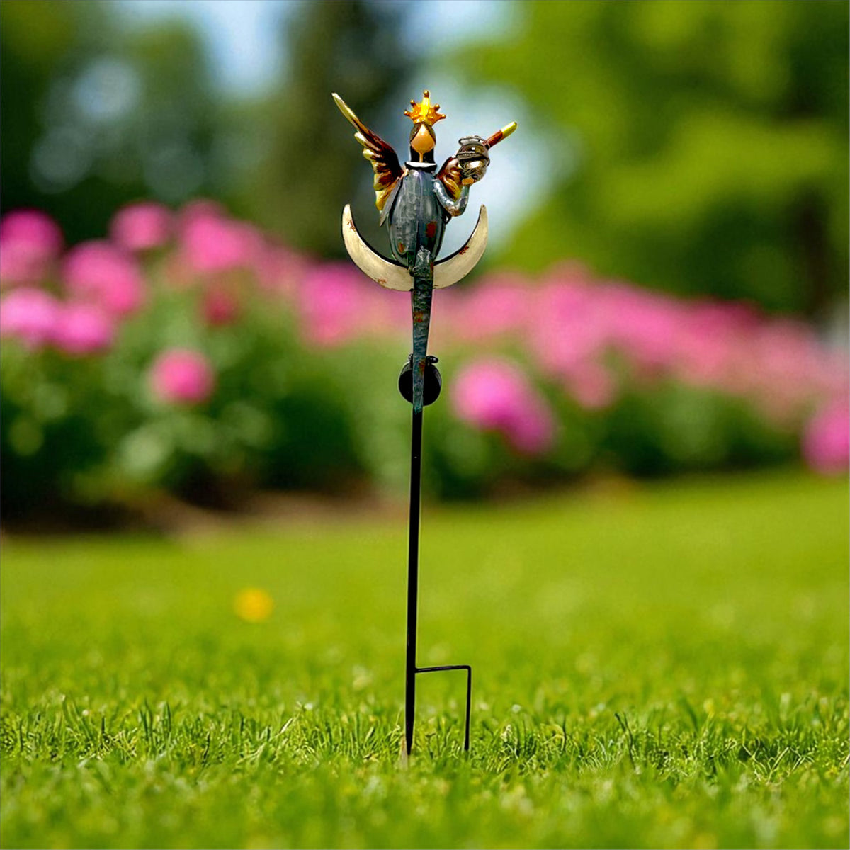 The back of an angel garden stake shows outstretched wings and a crescent detail against a lawn.