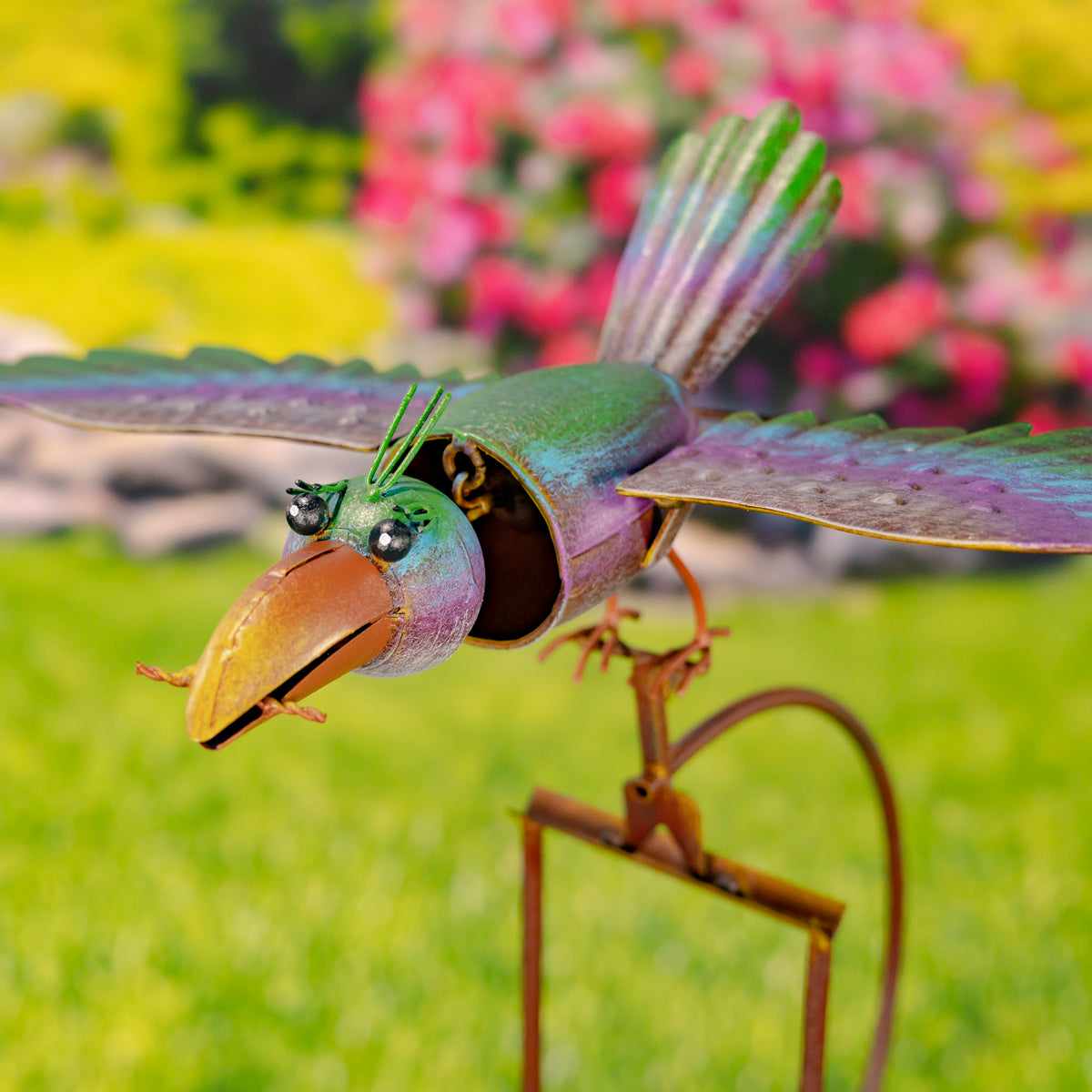 Close-up of green, blue and purple cockatoo with wings extended in a garden
