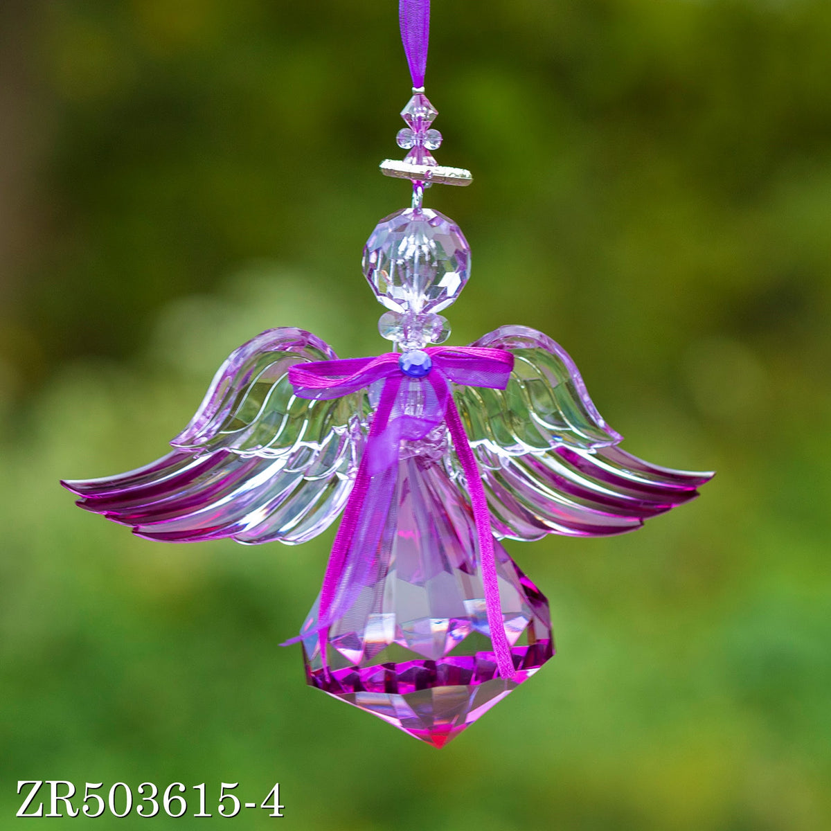 Close view of a dangling purple angel with broad feathered wings and a sparkling faceted body.