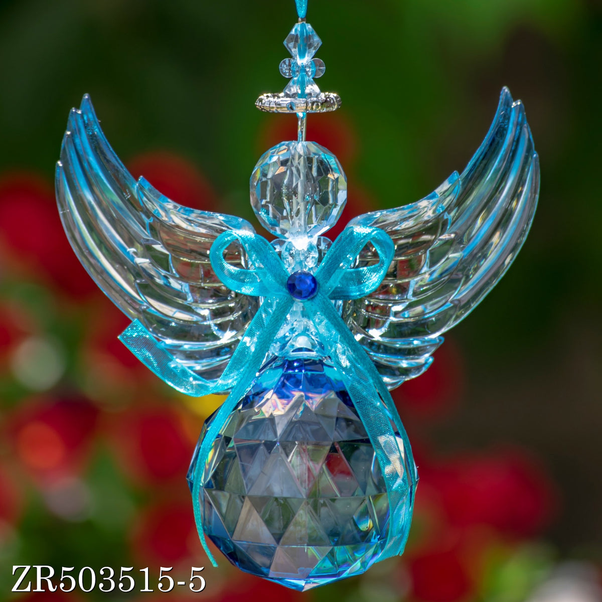A hanging acrylic angel with outstretched clear wings and a blue bow, shown against a dark blurred backdrop.