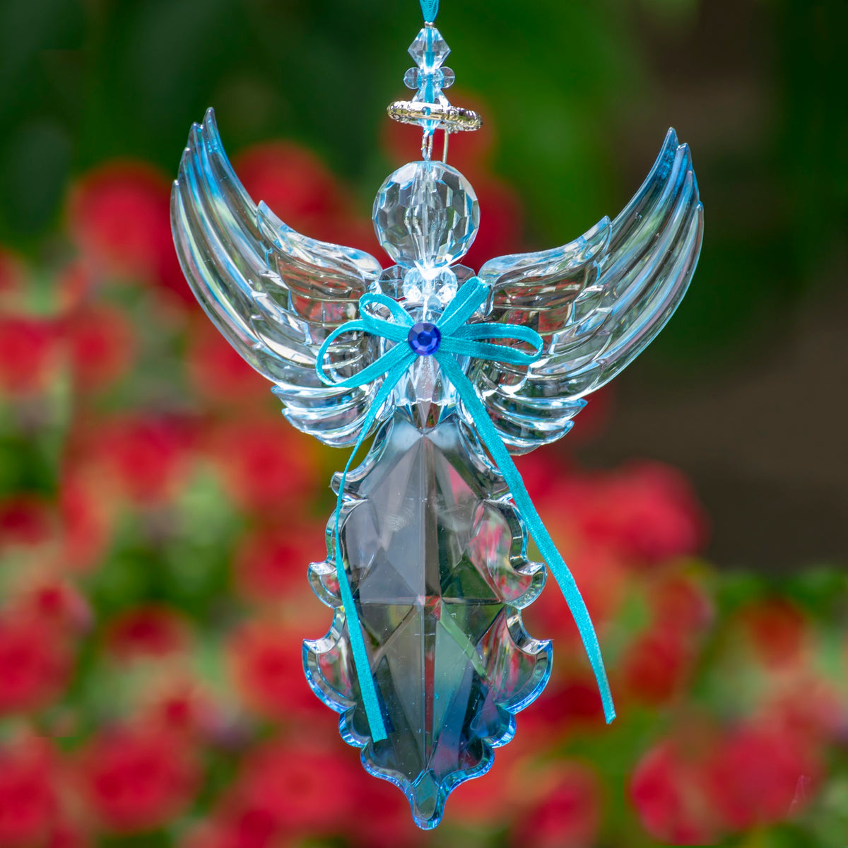 Blue angel ornament viewed from an angle, its clear wings lifted upward around a faceted body.
