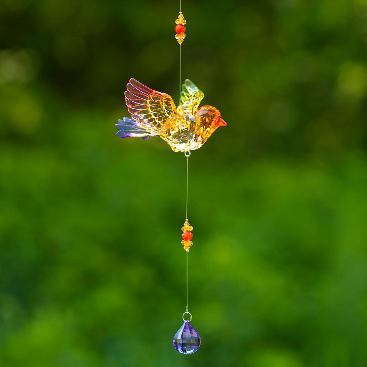 Warm-toned acrylic bird ornament with spread wings, orange bead accents and a blue-purple teardrop dangle.