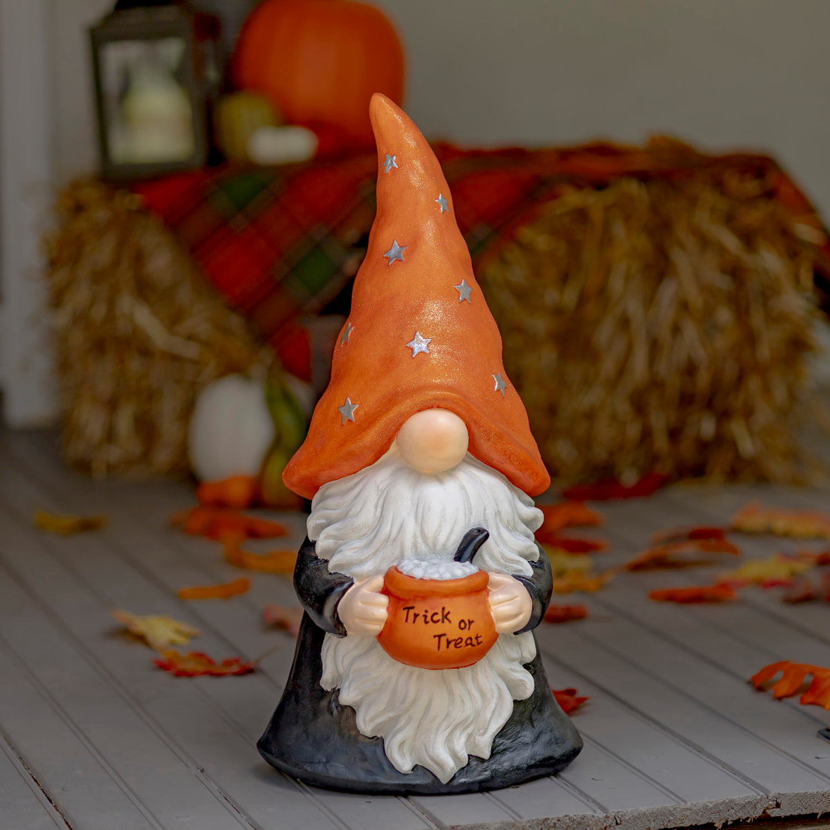 Halloween gnome statue holding a trick-or-treat pot in a fall-themed display