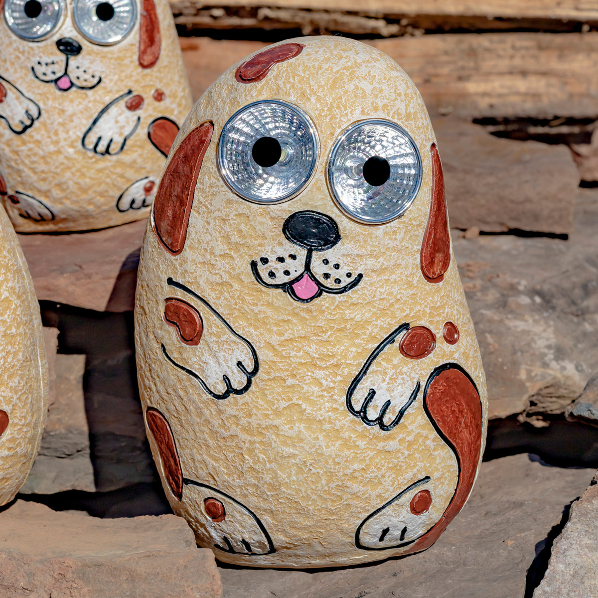Close-up of a tan rock-shaped dog ornament with oversized shiny eyes and painted brown spots.