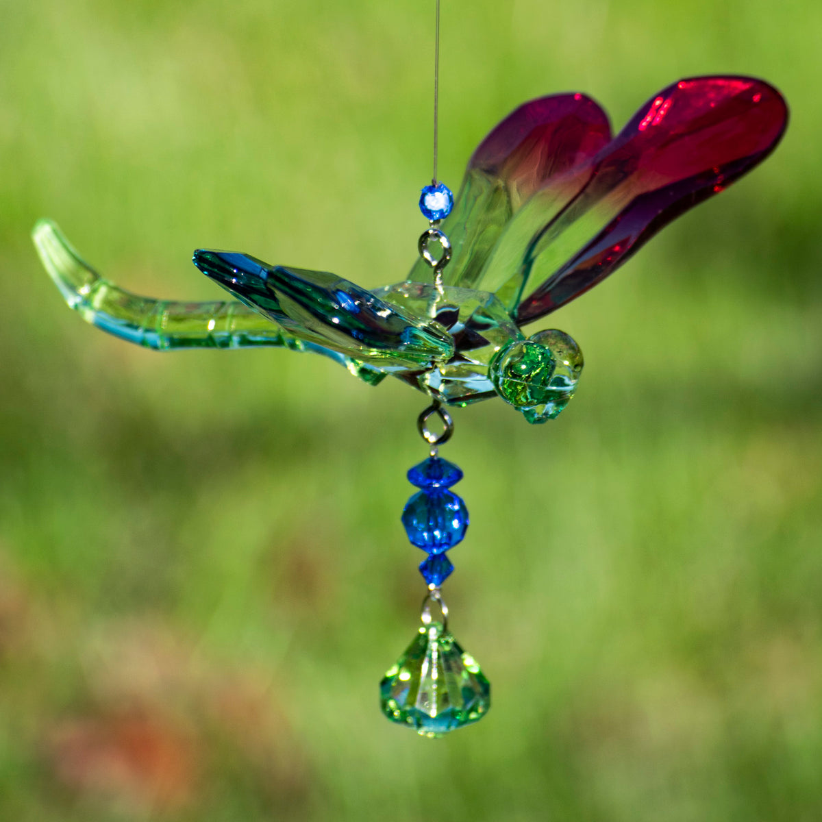 Close-up of a blue-green dragonfly ornament with jeweled beads hanging beneath it.