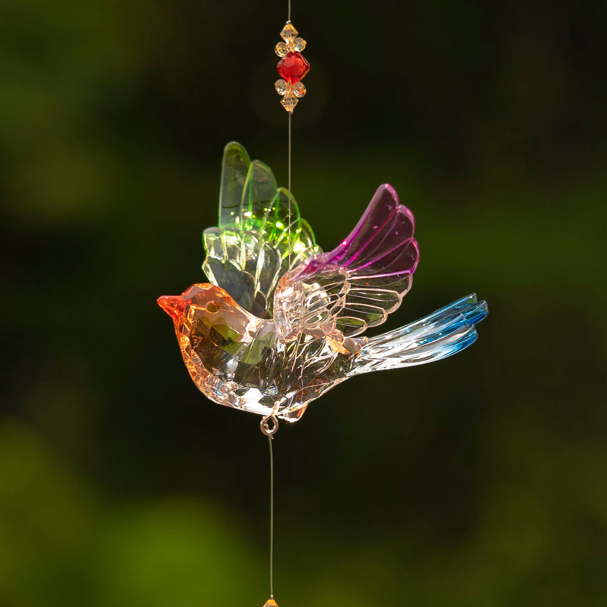Close view of a clear hanging bird ornament with colorful wings and small beads above and below.