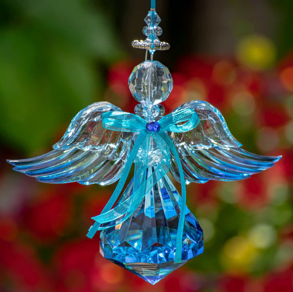 Hanging angel with wide swept wings, long turquoise ribbon streamers and a deep blue faceted skirt.