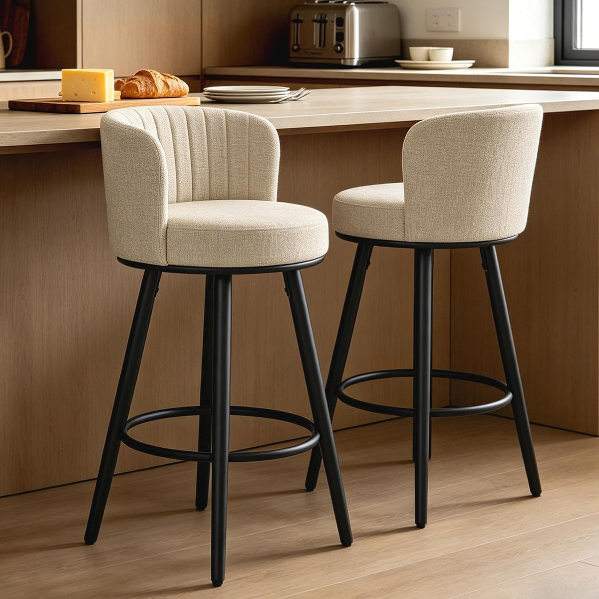 Two beige swivel bar stools beside a wood island showing the circular footrest and tapered black metal legs