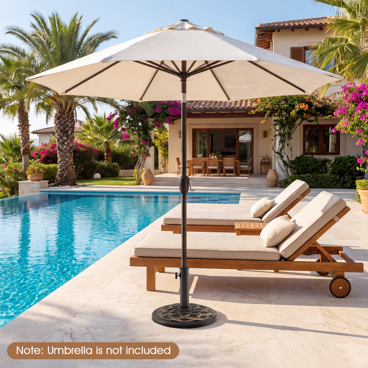A cream patio umbrella stands on a round base beside a pool and two wooden lounge chairs.