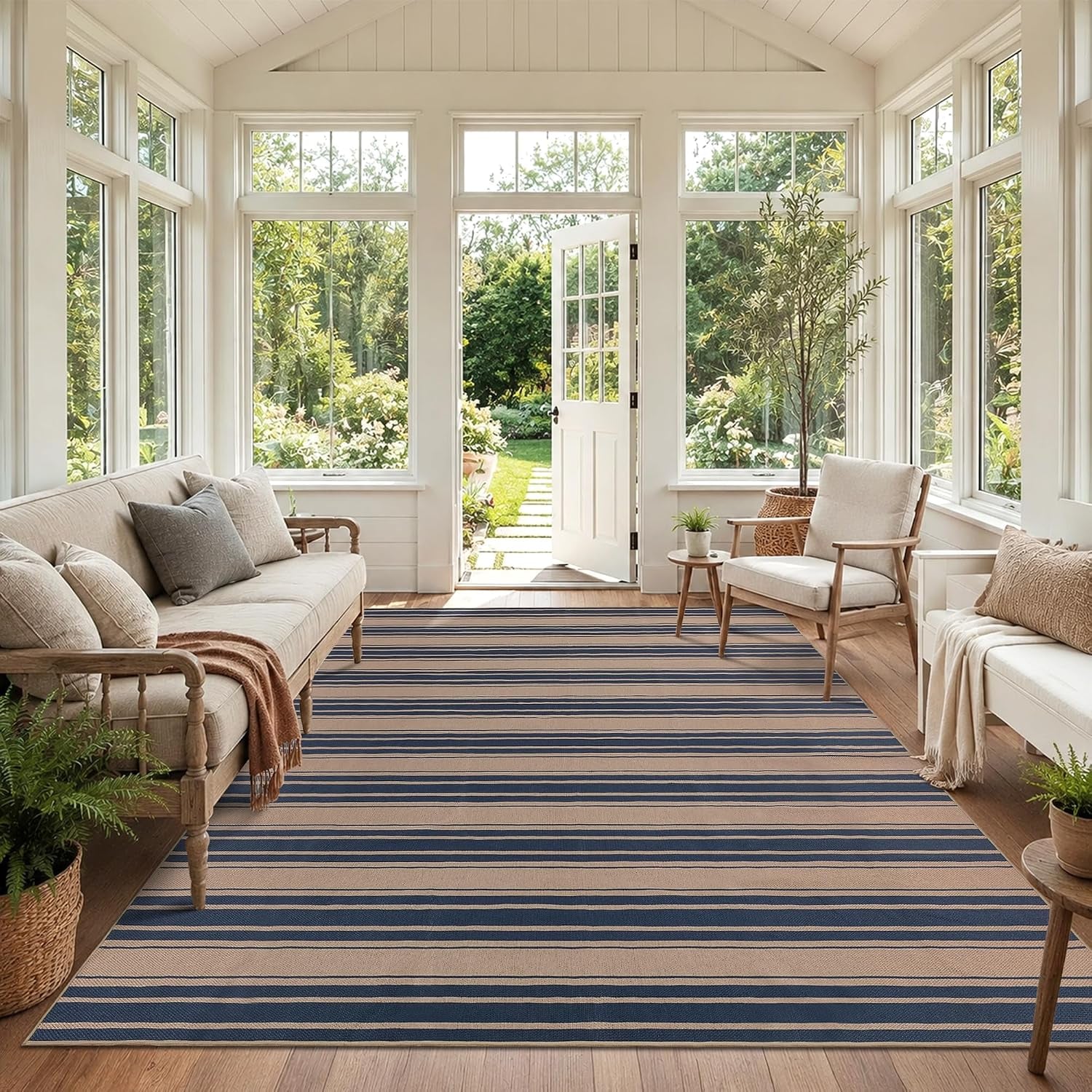 Wide striped navy and beige rug filling a bright sunroom with seating and large windows.