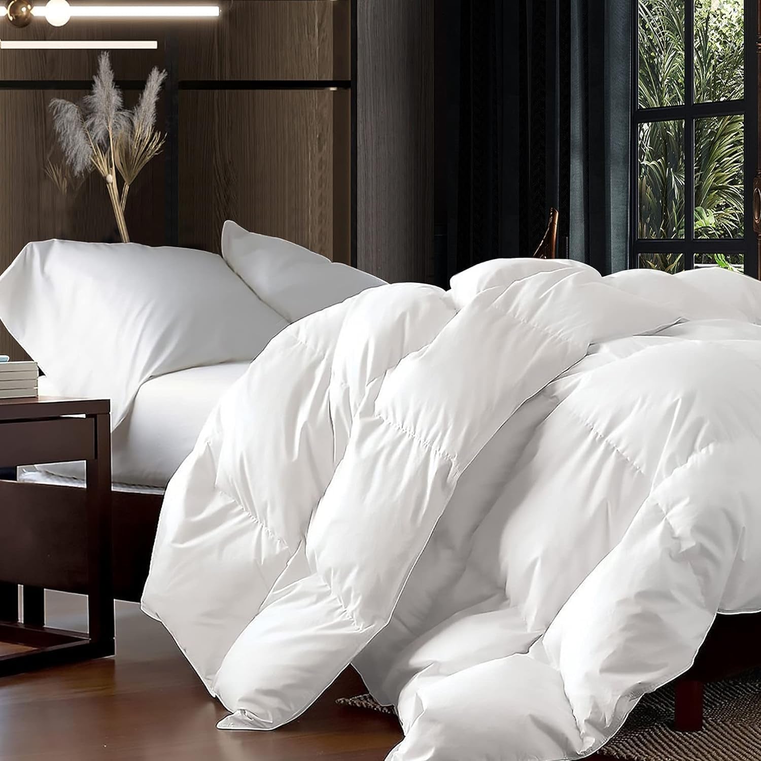 Close side view of a fluffy white down comforter spilling over the edge of a low wooden bed.