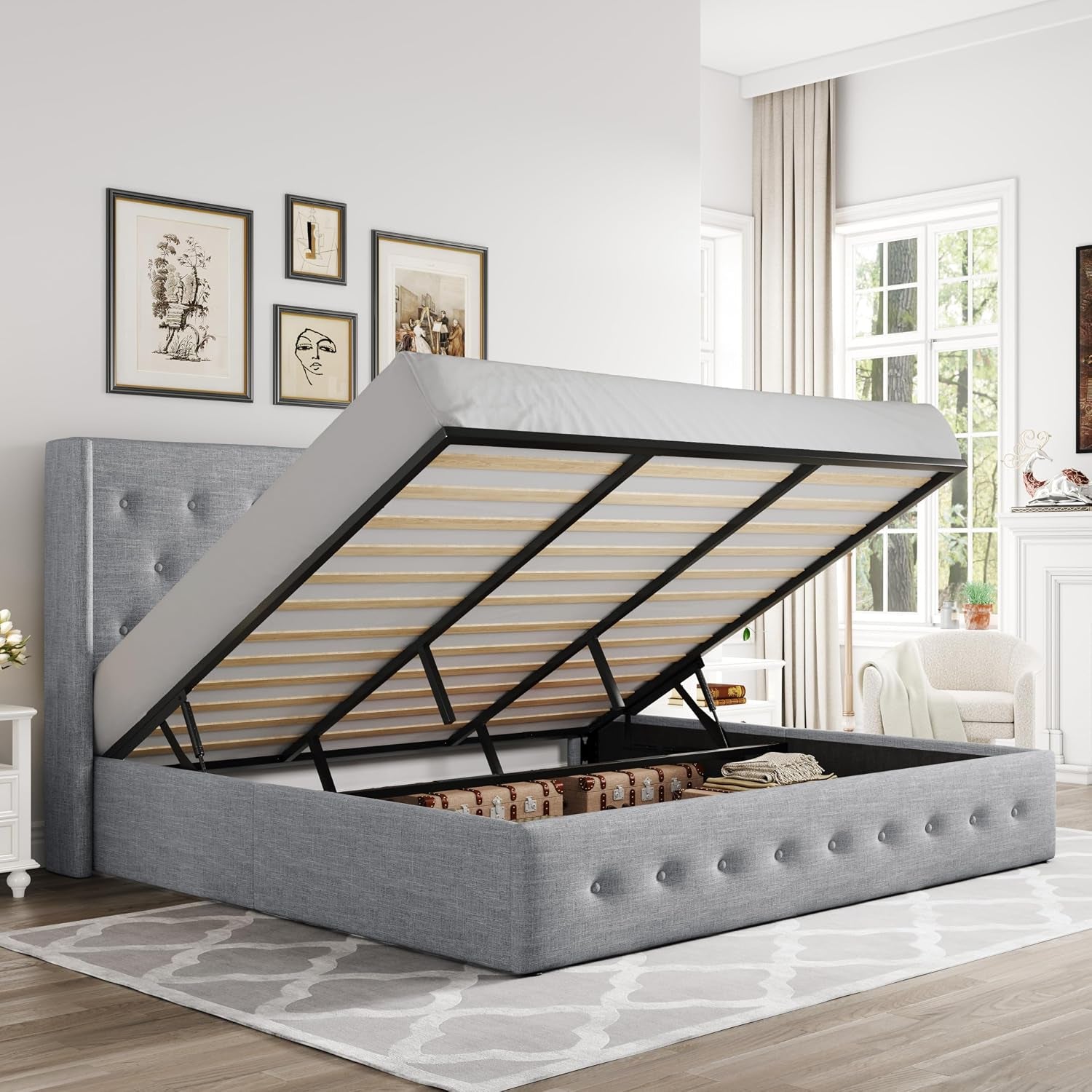 Angled room view of a medium-gray upholstered gas-lift bed with slatted base lifted and storage compartment visible.