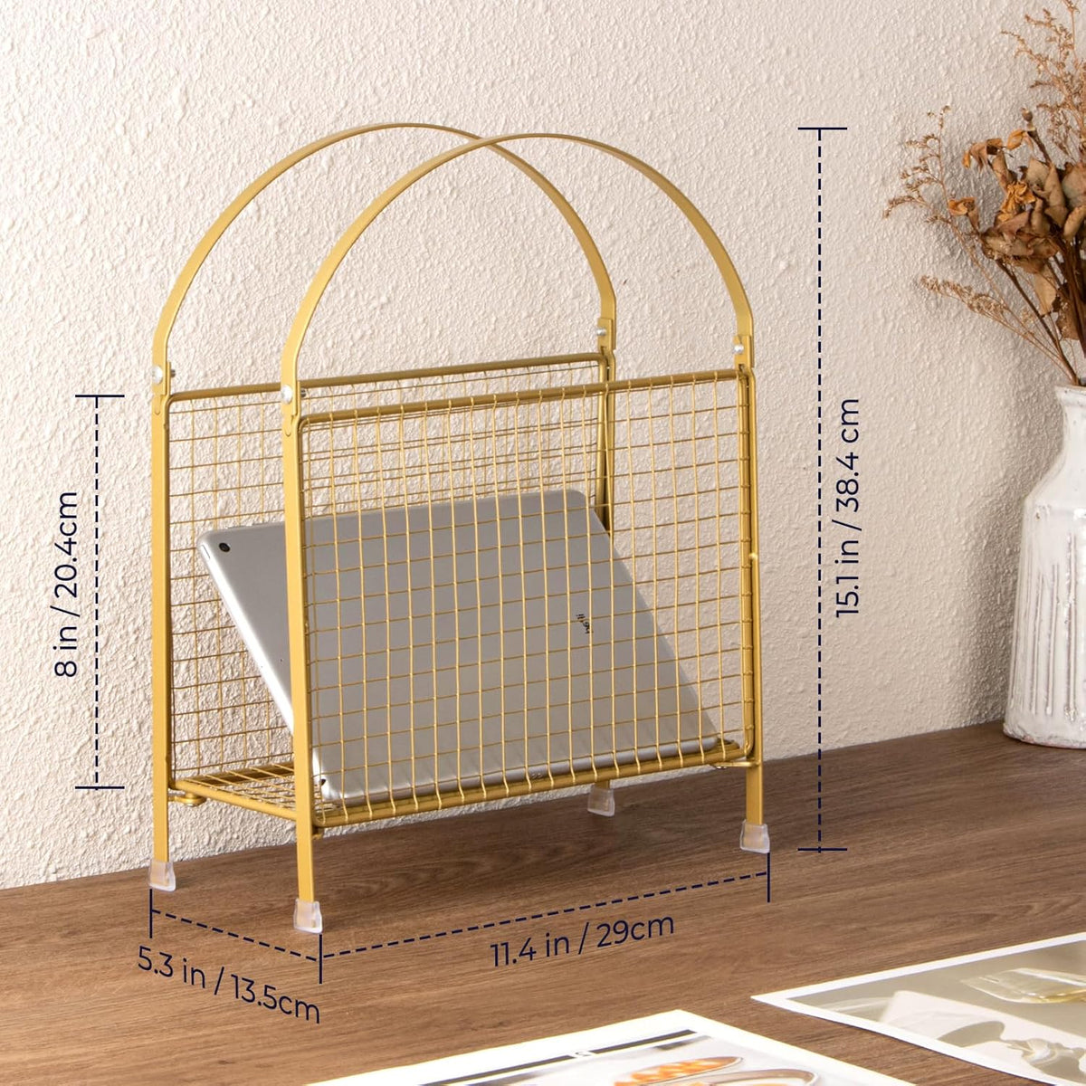 Angled front view of gold freestanding rack holding a laptop and stacked magazines against a wall