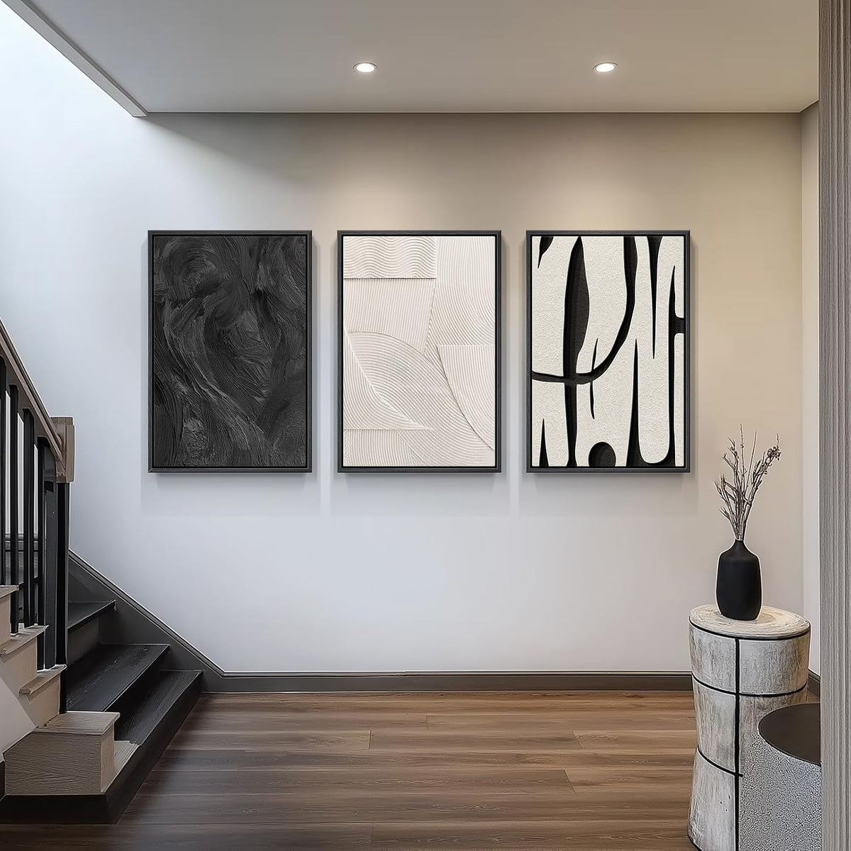 Three framed abstract canvas panels hung vertically in a stairwell with wood flooring and recessed ceiling lights