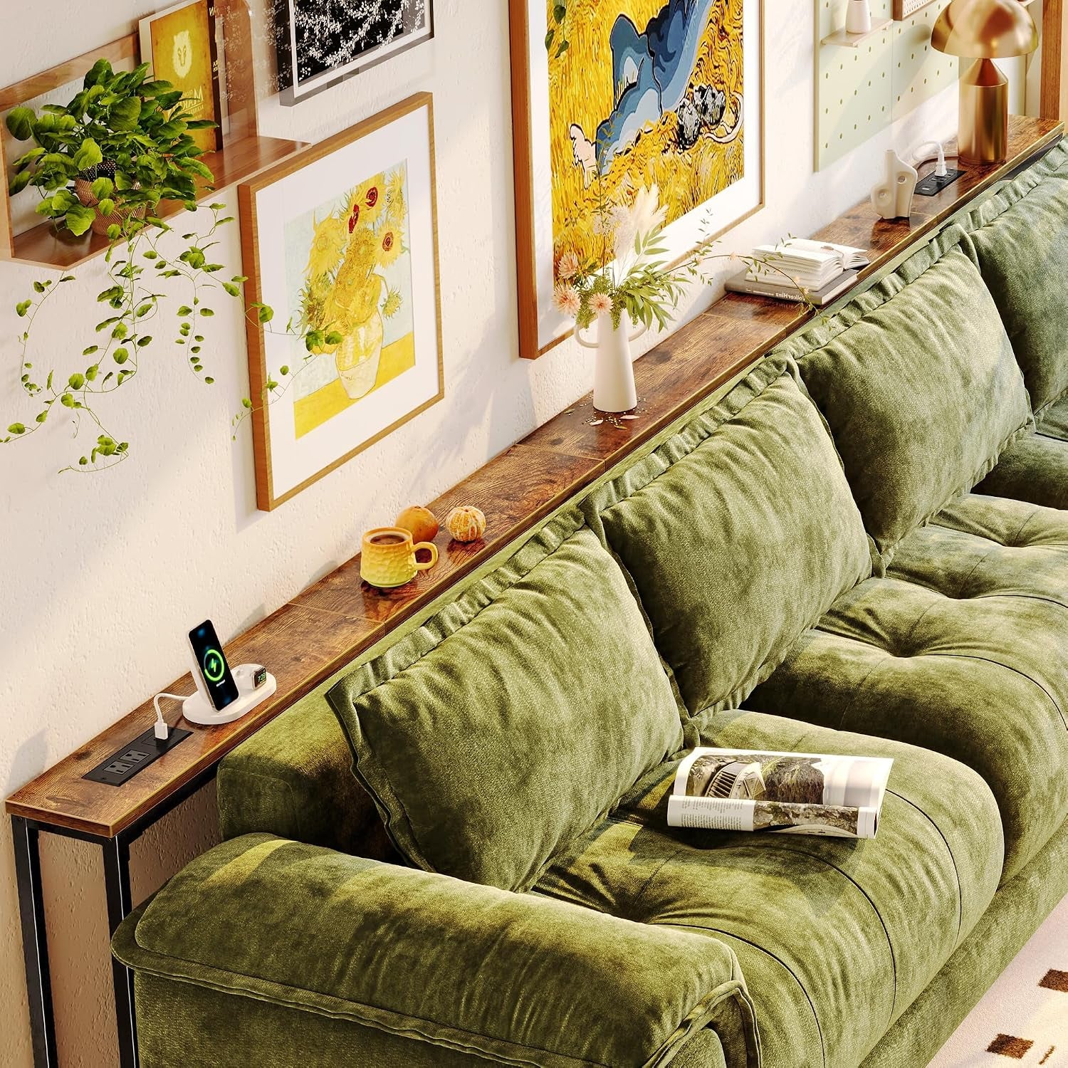 Long rustic brown console table styled with art, vase and lamp behind a plush green sectional.