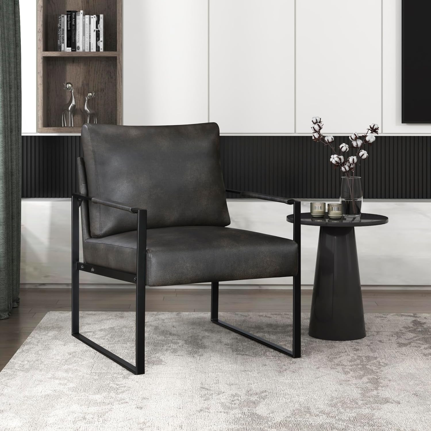 Single brown faux-leather armchair with black metal frame beside a small round black side table in a modern living space.