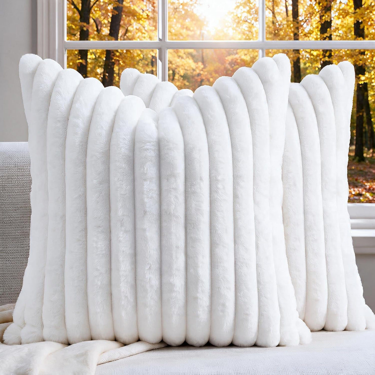 Front view of a white ribbed faux-fur throw pillow propped against a couch with fall trees visible.