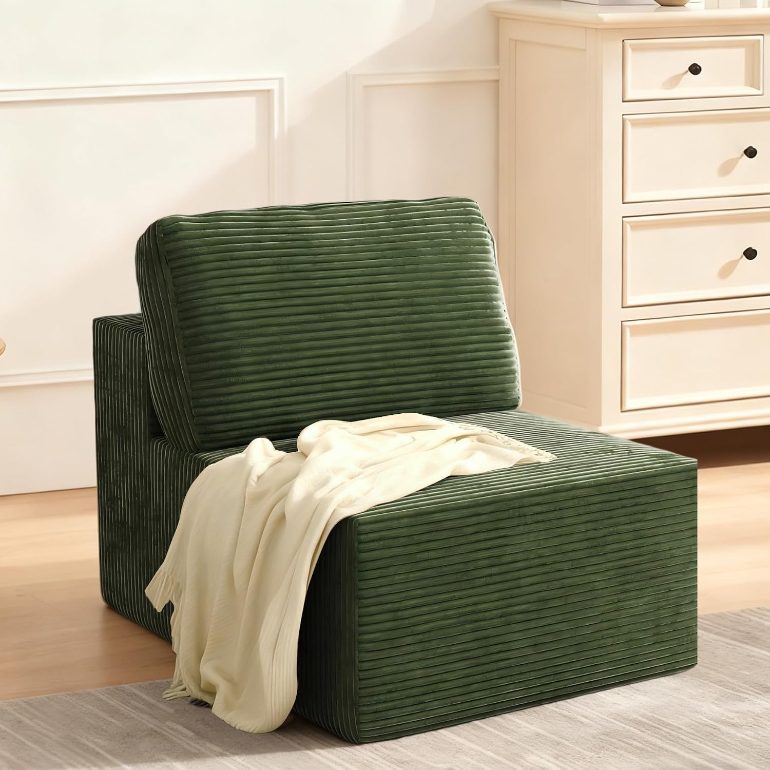 Side view of a single armless modular sofa seat in green ribbed fabric with a pale cream throw on top.