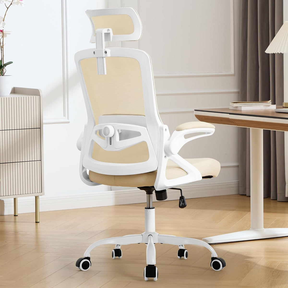 Rear three-quarter view of a beige mesh chair with white frame beside a desk and lamp.