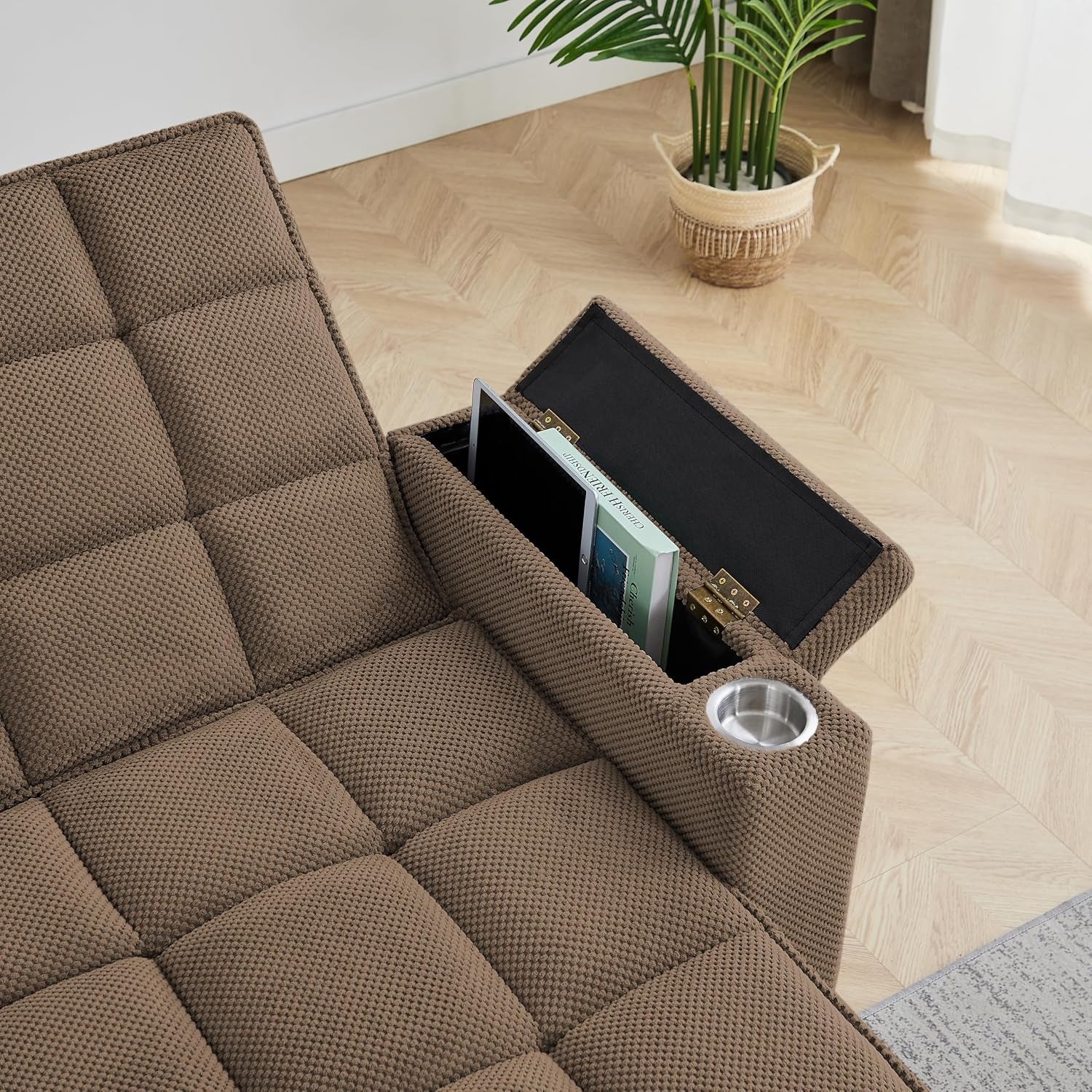 Close-up of brown tufted seat and open armrest storage with a stainless cup holder