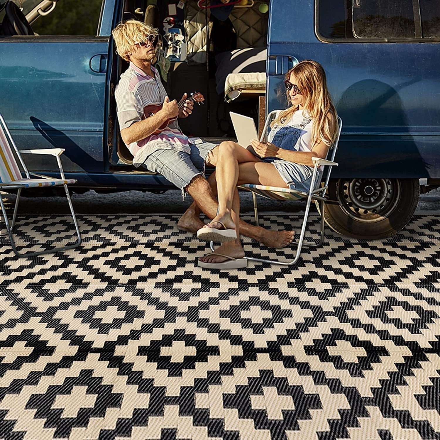 Couple seated by a van on a black-and-cream geometric outdoor rug.