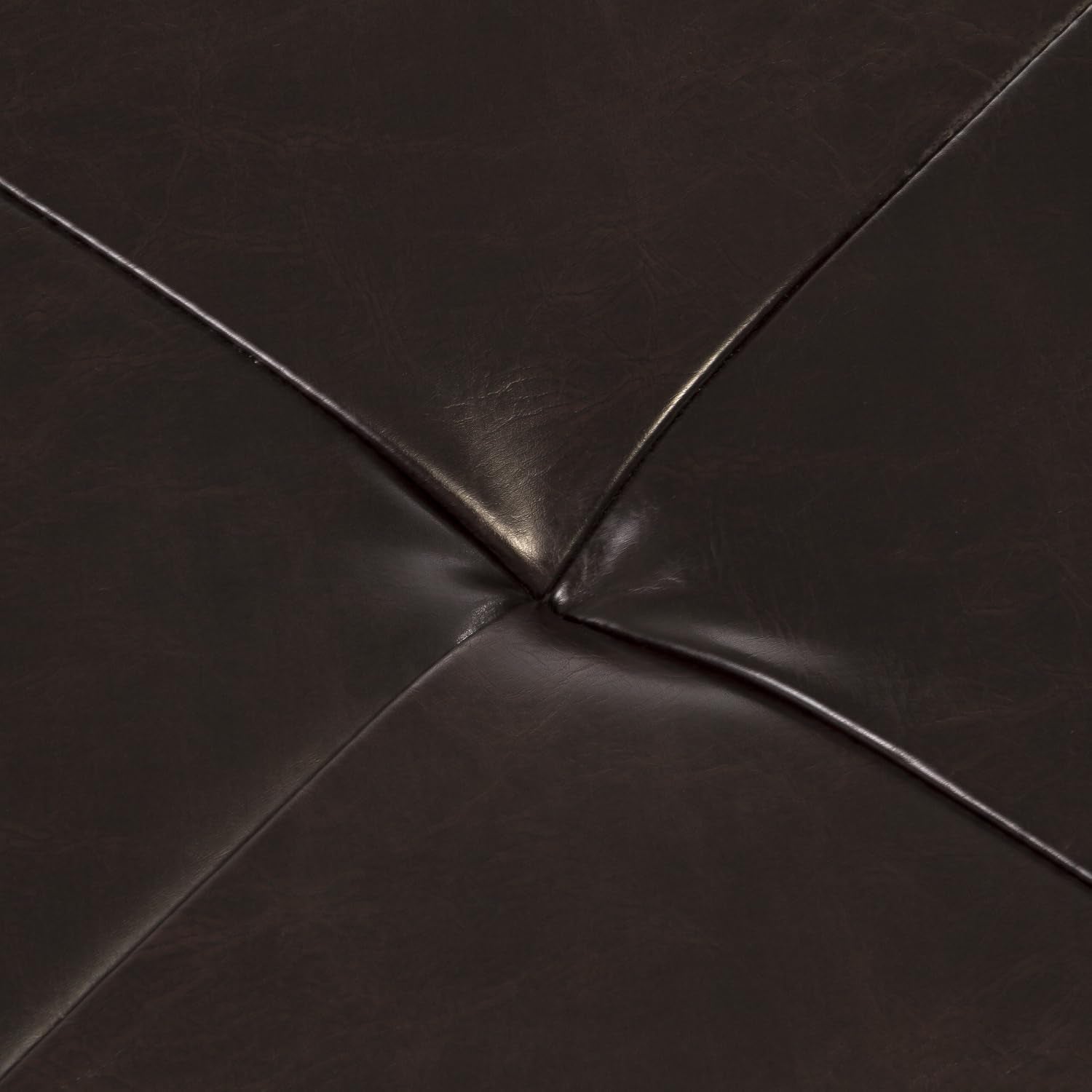 Top close-up of brown bonded leather tufted cushion showing the X-shaped seam and padded surface