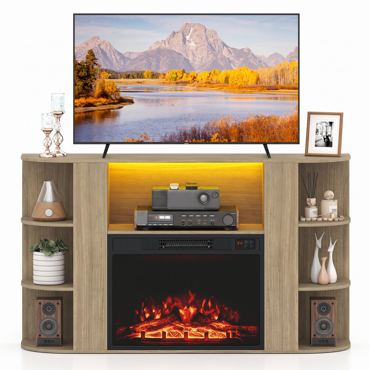 Light wood fireplace TV stand shown straight on, with a glowing fire, yellow-lit shelf, speakers, and television.