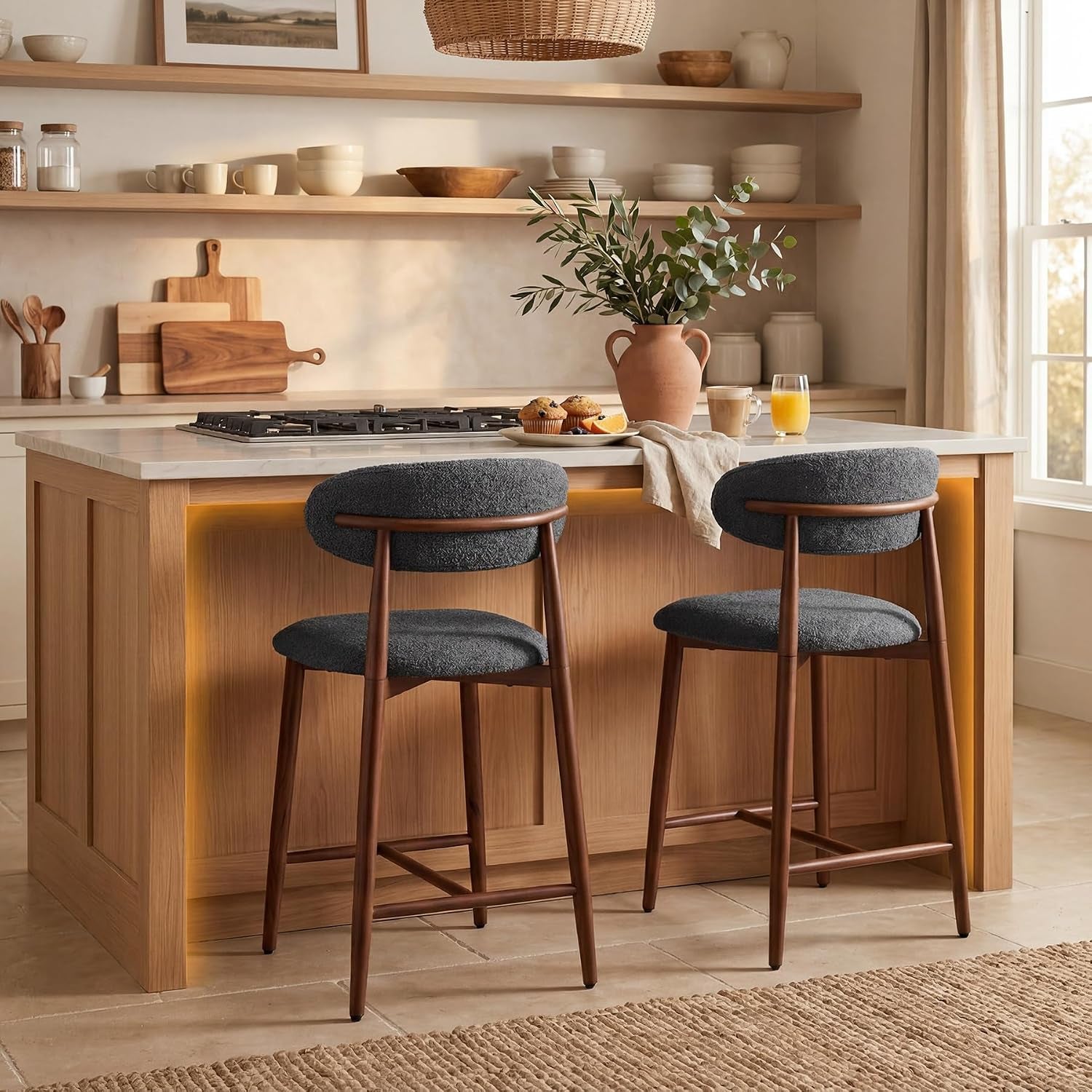 Two dark charcoal upholstered counter stools with warm brown tapered legs at a light wood kitchen island.